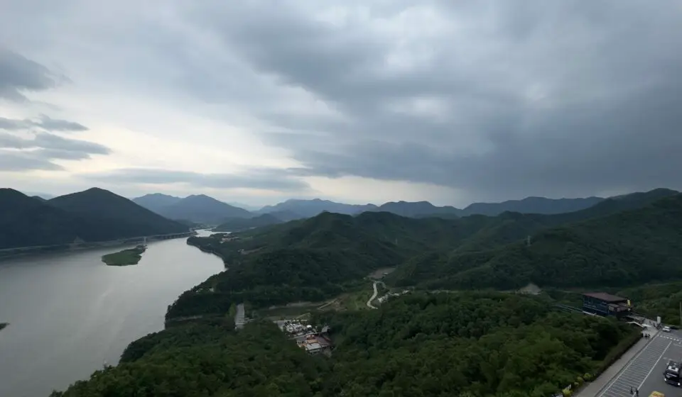 Scenic landscape view from the observation deck of 만천하스카이워크 in Danyang, South Korea, featuring winding river, forested mountains, and expansive sky.