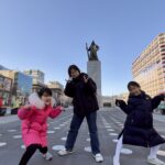 Mother and her two daughters posing in front of the statue of Admiral Yi Sun-sin at Gwanghwamun Square in Seoul, South Korea.