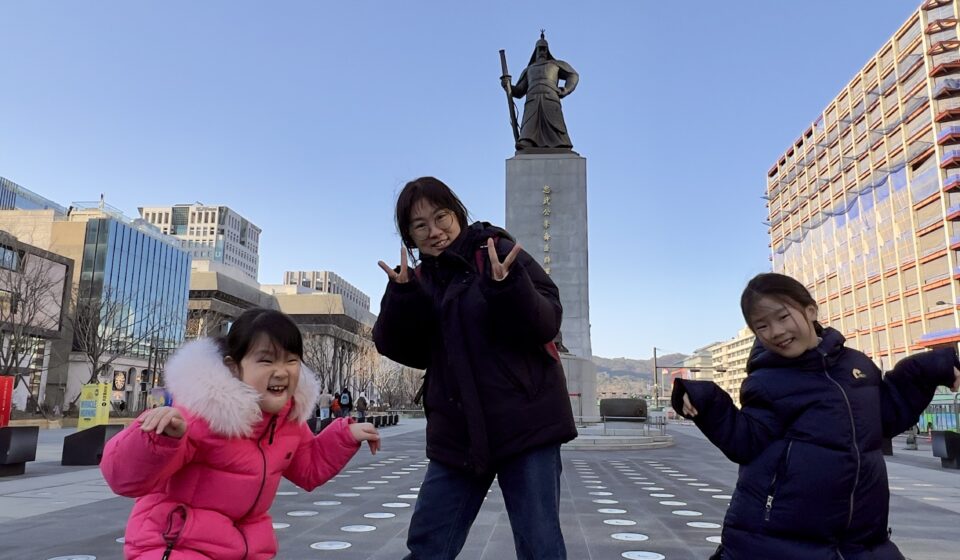Mother and her two daughters posing in front of the statue of Admiral Yi Sun-sin at Gwanghwamun Square in Seoul, South Korea.